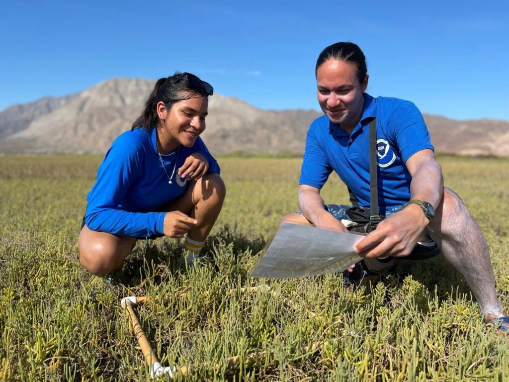 Two people in blue ODI shirts conducting outdoor fieldwork.