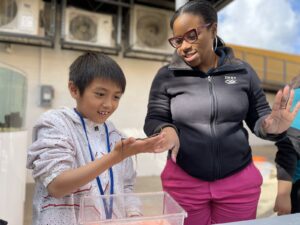 Jeanette Davis, a Scientist-in-Residence, examines a brittle star with a student during a program activity.